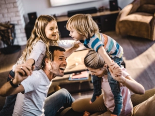 Familie mit zwei Kindern tobt ihm Wohnzimmer und hat Spass